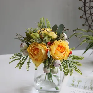 Detailed macro view of vibrant yellow artificial peonies and green foliage in a glass vase