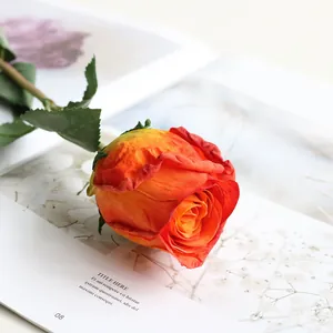 Detailed close-up view of an artificial orange silk rose with realistic burnt edge petals