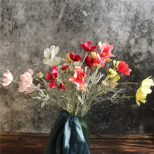 Fiori di cosmos artificiali colorati elegantemente disposti in un vaso verde scuro