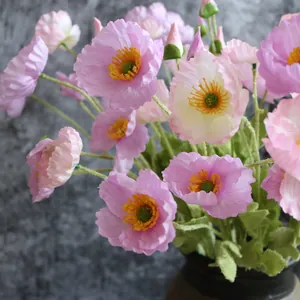 Primer plano de amapolas artificiales rosas en un jarrón con fondo oscuro
