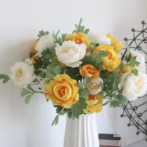 Detailed view of artificial yellow and white ranunculus flowers in a white vase