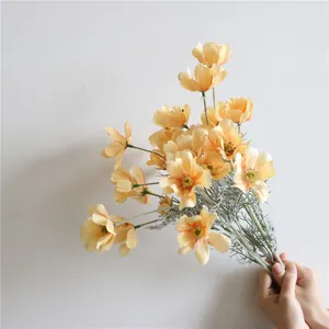 Primo piano di un bouquet tenuto in mano di fiori artificiali Cosmos in seta arancione