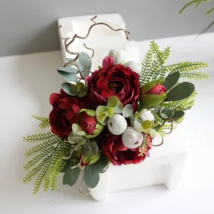 Close-up detail of a dark red Nordic style artificial peony bouquet with lush green leaves