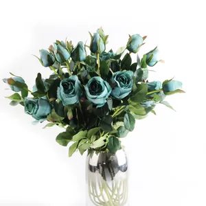 Vue détaillée de roses artificielles bleu canard dans un vase métallique élégant