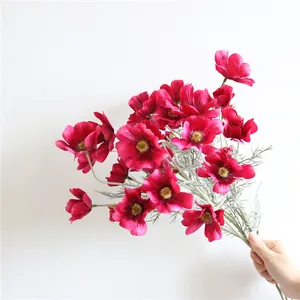 Una mano che tiene un bellissimo bouquet di fiori di cosmo artificiali color magenta