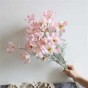 Vista dettagliata di una mano che tiene un bouquet di cosmee artificiali rosa chiaro