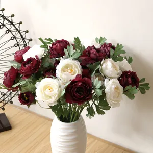 Detailed view of elegant burgundy and white silk peony flowers in a textured white vase