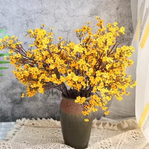 Nahaufnahme von künstlichen gelben Schleierkrautblüten in einer rustikalen Vase