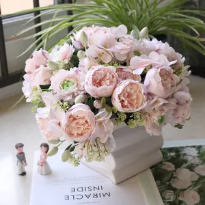 Detalle de ramo de peonías artificiales rosas en un elegante florero blanco moderno.