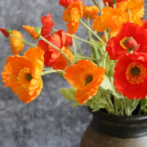 Primer plano macro de amapolas de Islandia de seda naranja y roja en un jarrón rústico