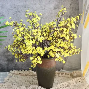 Leuchtend gelbe künstliche Seiden-Schleierkrautblüten in einer rustikalen Keramikvase