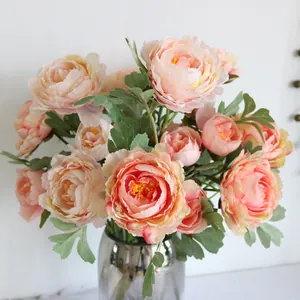 Close-up of realistic silk Persian buttercup flowers in a smoky glass vase for home decor.