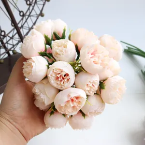 Detailed macro view of a 27-head artificial pink tea rose bouquet being held by hand.