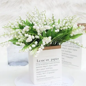 Elegant white artificial lily of the valley bouquet in a decorative paper bag