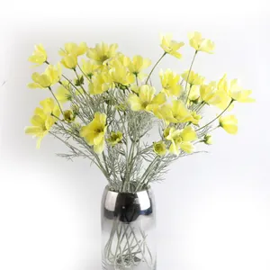 Dettaglio di fiori di cosmea artificiali gialli in un elegante vaso di vetro argentato