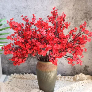 Detail von roten künstlichen Schleierkraut-Zweigen in einer Vintage-Vase auf Spitzendecke