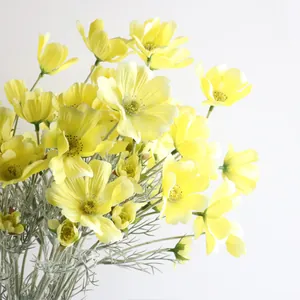Dettaglio ravvicinato di fiori di cosmo gialli artificiali con foglie argentate