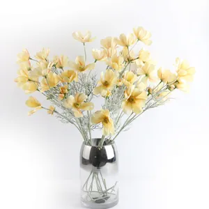 Eleganti fiori di cosmo artificiali gialli in un vaso di vetro sfumato metallico