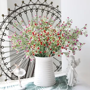 Ramo de paniculata artificial en jarrón blanco con elegantes figuras decorativas