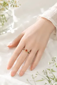 Detailansicht eines eleganten chinesischen Perlenrings mit rotem Stein und Goldakzenten an der Hand