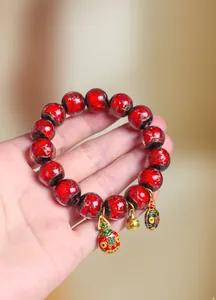 Gros plan d'un bracelet en perles de verre rouges avec breloques porte-bonheur dorées