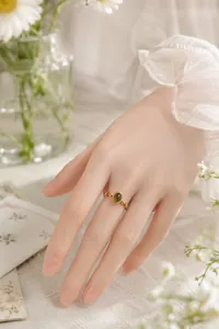 Detailansicht eines Goldrings im Vintage-Stil mit grünem Stein und orangen Perlen
