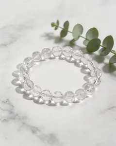 Détail d'un bracelet en quartz clair naturel avec perles en forme de météorite sur marbre.