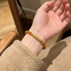 Détail d'un bracelet en perles d'agate naturelle avec des anneaux dorés porté au poignet
