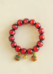 Gros plan d'un bracelet en perles de verre rouge avec breloques dorées