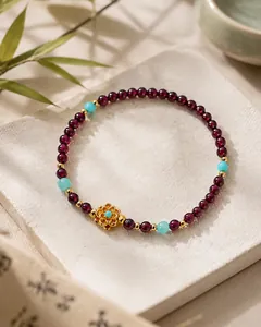 Vue détaillée d'un bracelet en grenat avec fleur dorée et touches de turquoise.