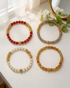 Détail de quatre bracelets en agate naturelle aux couleurs variées avec perles dorées sur table