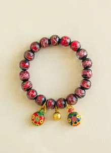 Détail de bracelet en perles de Liuli rouge avec breloques en émail et or