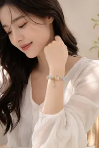 Detailansicht eines Armbands aus Aquamarin und weißem Kristall am Handgelenk des Models