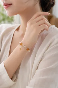 Nahaufnahme einer Frau, die ein elegantes, perlenbesetztes Naturkristallarmband trägt.