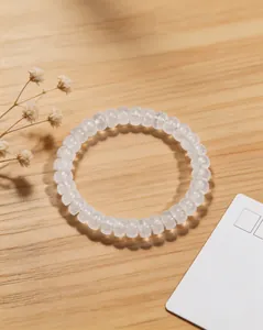 Gros plan montrant la texture facettée d'un bracelet en cristal de roche clair sur bois.