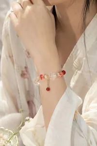 Nahaufnahme eines eleganten Naturkristall-Armbands mit roten Akzenten am Handgelenk