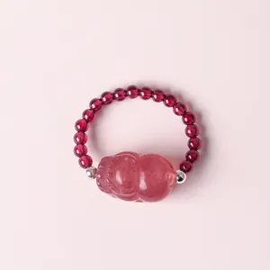 Detailansicht eines Rings aus Granatperlen mit einem rosa geschnitzten Kristall-Pixiu-Anhänger