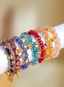 Makroaufnahme bunter Glasperlenarmbänder mit goldenen Tier- und Münzanhängern