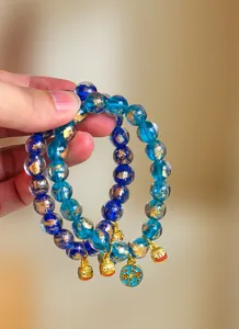 Nahaufnahme von blauen Glasperlenarmbändern mit goldenen Tieranhängern und Blattgold