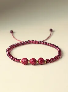 Primo piano di bracciale con perle di granato e cinabro e distanziatori dorati portafortuna.