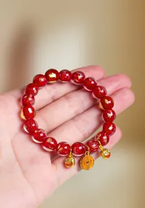 Detaillierte Ansicht des roten Glasperlenarmbands mit Goldfolie und Glücksbringern