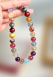 Detalle de un collar de cuentas de cristal natural multicolor sostenido a mano