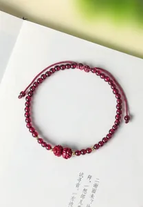 Macro dettaglio di un bracciale in granato naturale e cinabro con accenti dorati