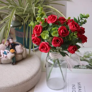 Detailed view of red artificial roses with eucalyptus leaves in a glass vase for home decor