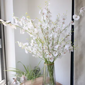 Elegant white silk dancing orchid flowers presented in a gold-rimmed transparent glass vase.