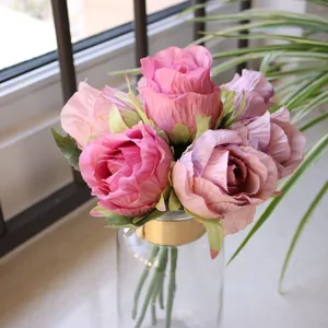 Detailed view of artificial pink roses in a clear glass vase for wedding decor
