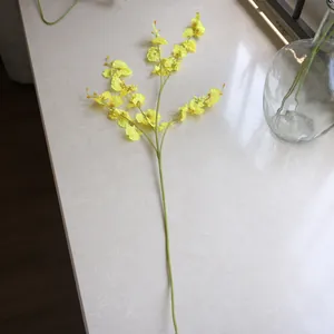 Single stem of yellow artificial Dancing Lady Orchid with five branches on a marble surface