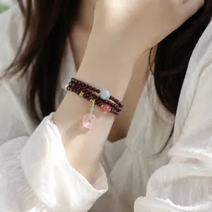 Élégant bracelet multi-rangs en grenat avec pendentif donut en quartz rose au poignet