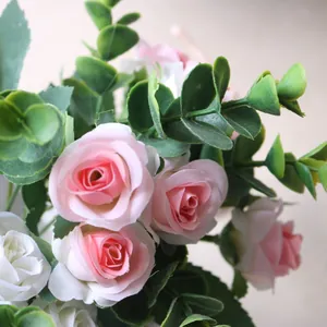 Close-up macro view of delicate artificial pink and white roses with green eucalyptus leaves