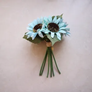 Close-up of artificial light blue sunflowers with green stems on marble background